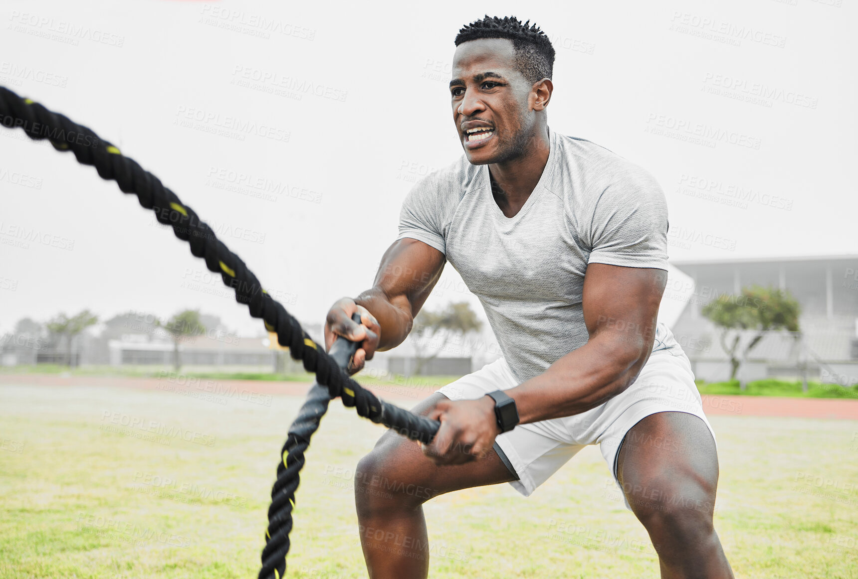 Buy stock photo Battle rope, black man and fitness with workout for strong arm muscle development, endurance and intensity on field. Male athlete, exercise and heavy cord in sports ground for conditioning and power