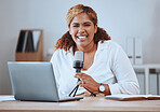 Portrait of smiling young mixed race female presenter using a mic and wireless laptop while doing her podcast sitting at home. Hispanic female blogger using equipment for her social media podcast