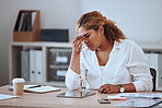 Businesswoman looking stressed with a headache. Upset businesswoman suffering a migraine. Entrepreneur frustrated with her failure. Depressed businesswoman sitting at her desk with a headache