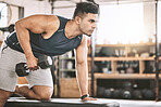 Serious bodybuilder lifting weights. Young athlete building strong muscles with dumbells. Focused healthy fit man doing arm curls. Muscular fitness trainer working out using an exercise bench