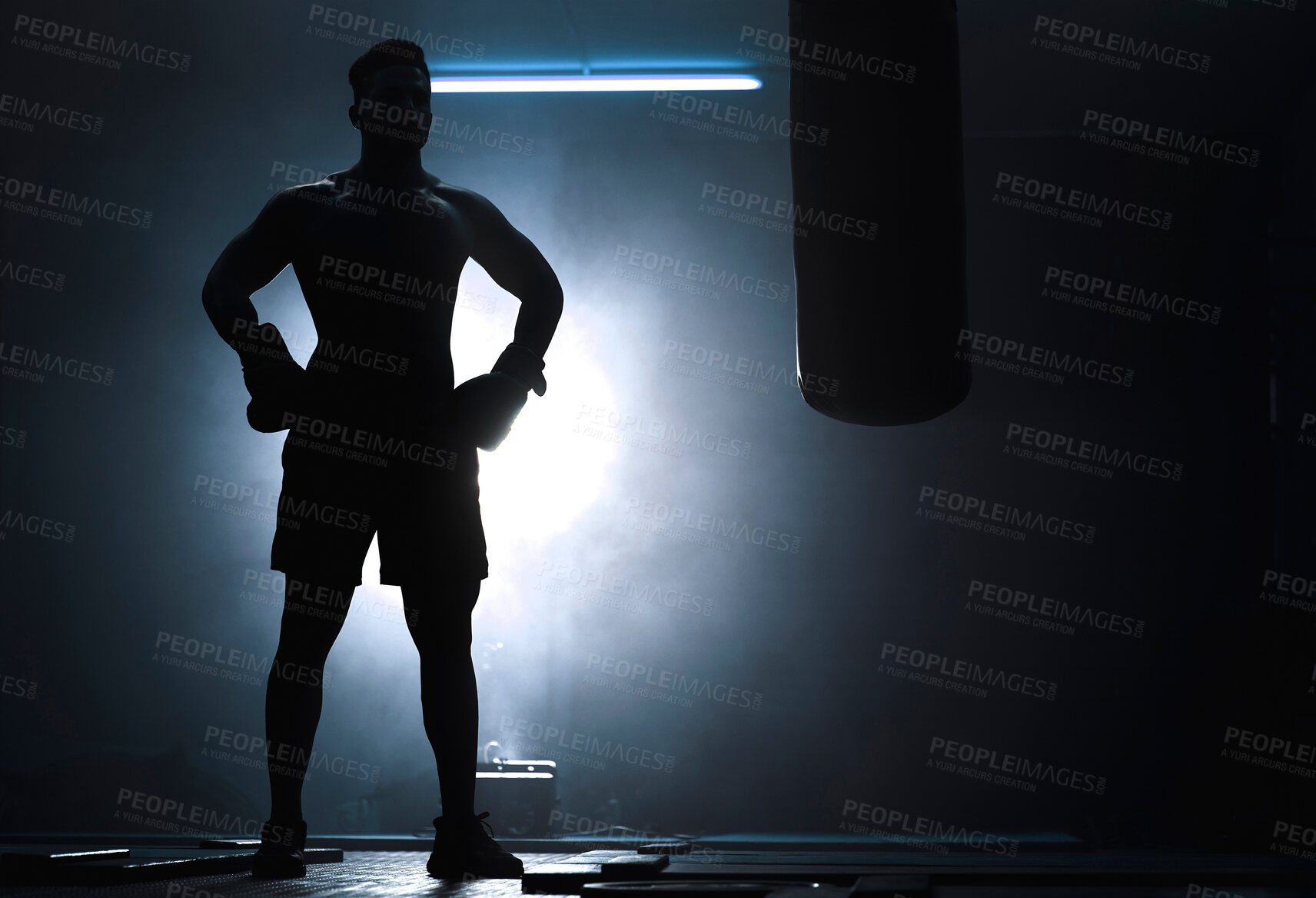 Buy stock photo Man, punching bag and silhouette boxer at gym, training practice and attack challenge for combat. Male person, smoke and dojo club aesthetic for fight competition, athlete and martial arts workout