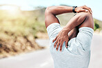 Rearview fit young mixed race man stretching before his exercise outdoors. Closeup male warming up and getting ready in preparation for a run or jog outside in nature. Endurance and cardio training