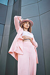 A young mixed race female posing in trendy fashionable clothing while chilling outside in the city. Hispanic woman showing the latest fashion collection with a cool style and hat 