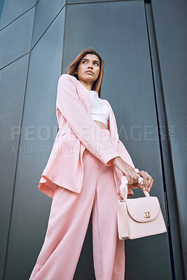 Buy stock photo Thinking, trendy woman and fashion in city with confidence, attitude and designer clothing. Stylish, pink suit and purse by building for outfit, urban downtown and gen z brand promotion on street