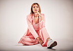 Portrait of a young mixed race female posing in trendy fashionable clothing while chilling on a floor of a studio. Hispanic woman showing the latest fashion collection with a cool style and sneakers