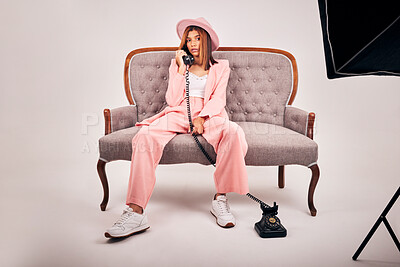 Buy stock photo Portrait, girl and fashion with telephone in studio for elegant clothes, formal suit and stylish photography. Confident, woman and relax with aesthetic hat, softbox and production on white background