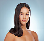 Portrait of a hispanic brunette woman with long lush beautiful hair posing against a grey studio background. Mixed race female standing showing her beautiful healthy hair