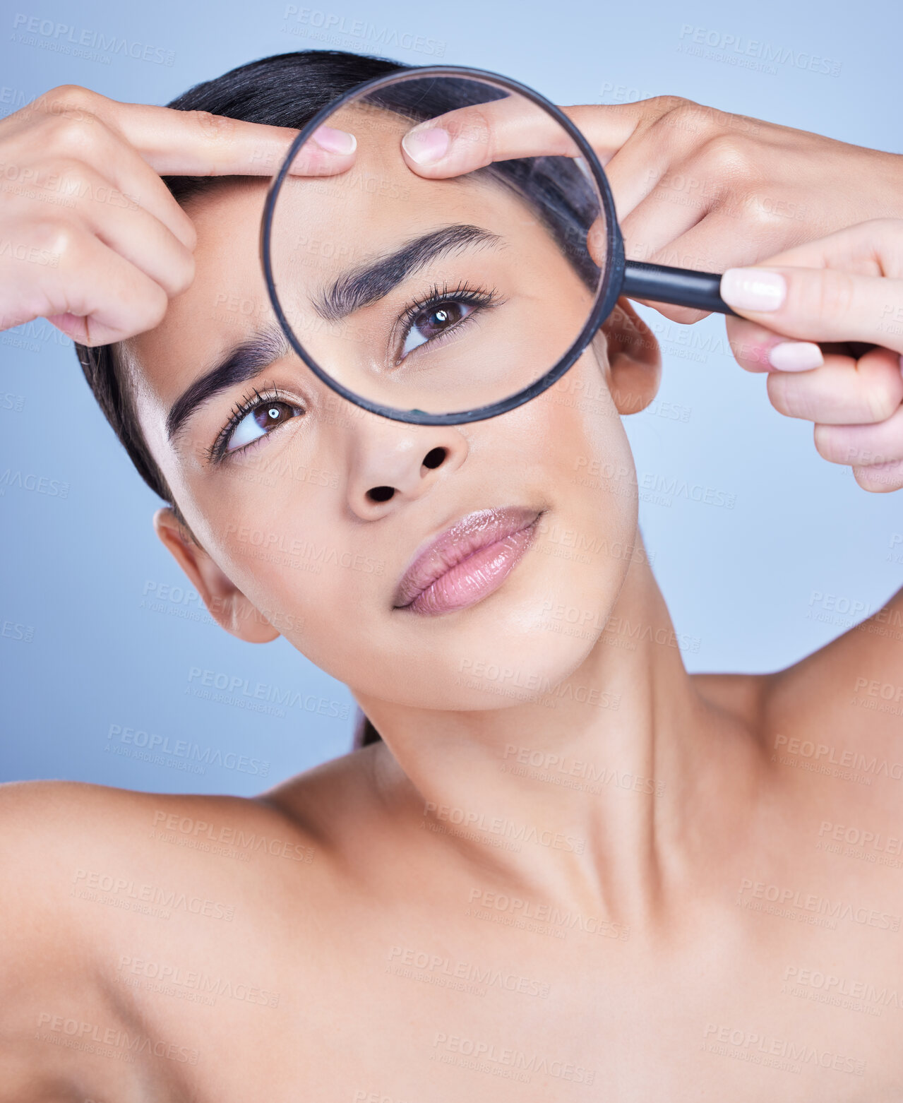 Buy stock photo Girl, skincare and magnifying glass in studio for dermatology, breakout inspection and check for pimples. Woman, loupe and blue background for facial treatment or self care, examination and wellness