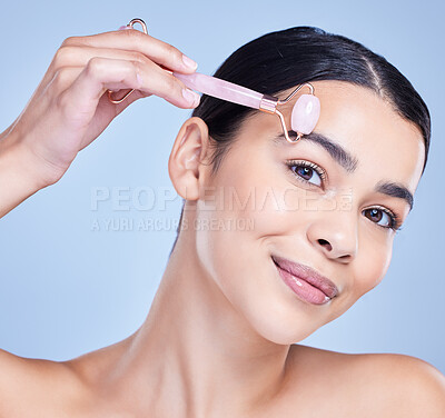 Buy stock photo Skincare, facial roller and portrait of woman in studio with lymph drainage massage routine. Beauty, rose quartz and person with crystal tool for face blood circulation with glow by blue background.