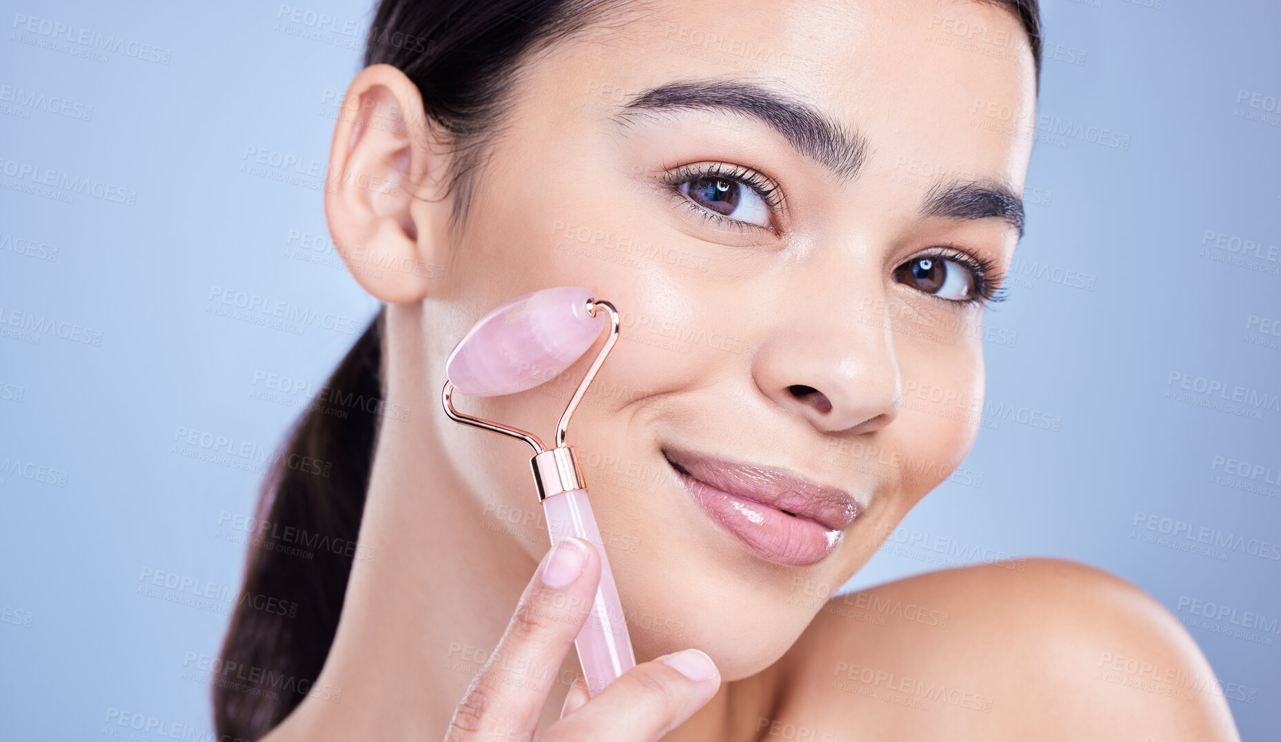 Buy stock photo Beauty, facial roller and portrait of woman in studio with lymphatic drainage routine for slimming. Skincare, rose quartz and person with crystal tool for face blood circulation by blue background.