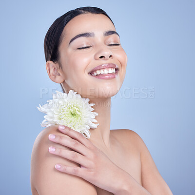 Buy stock photo Flower, relax or happy woman with natural beauty on blue background with smile, pride or glow. Face, confident or girl model in studio with floral cosmetics, plants or skincare for facial results