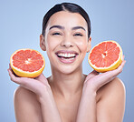 Portrait of a happy mixed race woman holding a grapefruit. Hispanic model promoting the skin benefits of citrus against a blue copyspace background