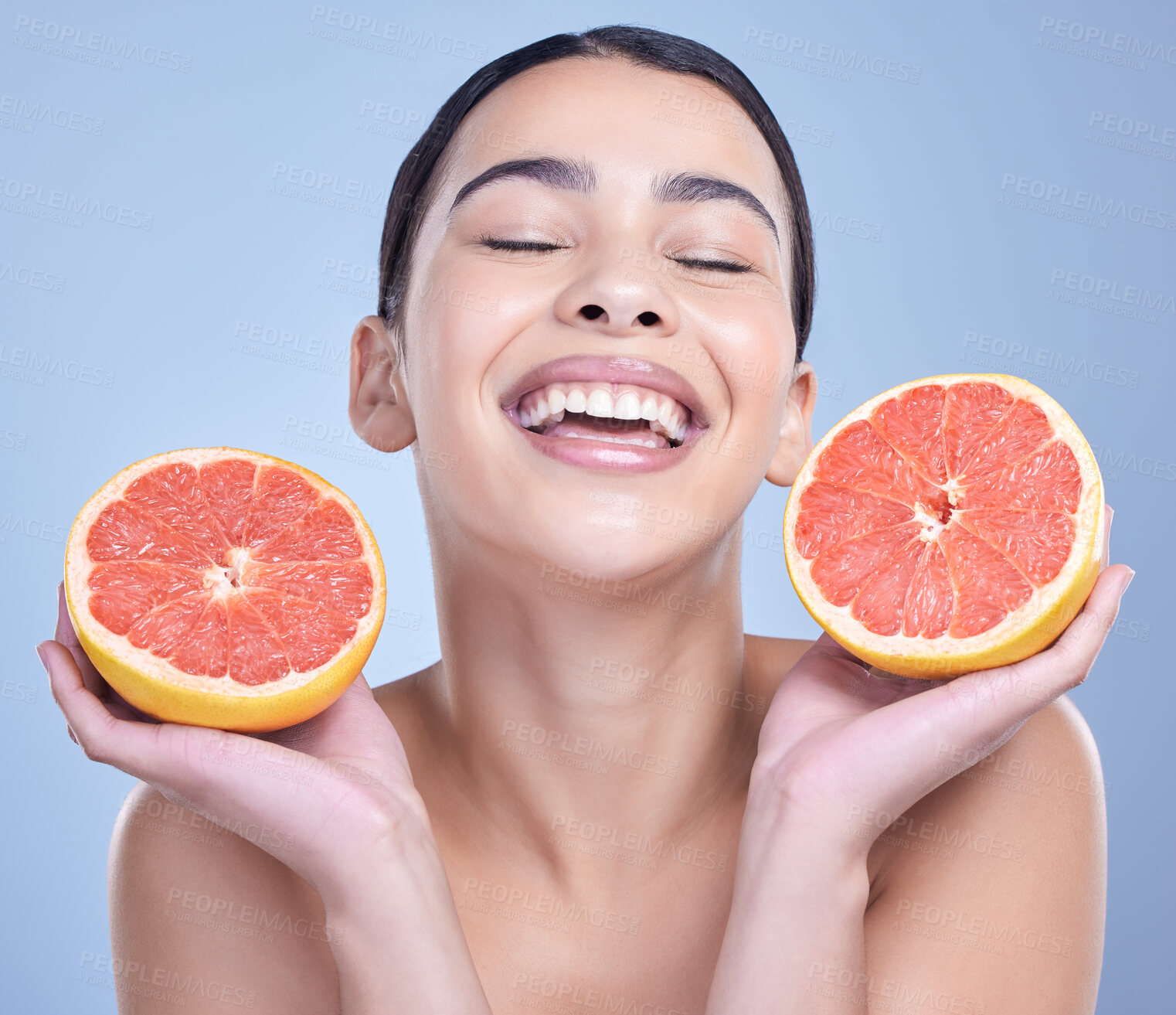 Buy stock photo Girl, grapefruit and happy in studio for skincare, organic and natural cosmetic with vitamin c or smile. Woman, eyes closed and fruit on blue background for sustainability, detox and healthy glow.