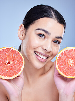 Buy stock photo Girl, grapefruit and portrait in studio for skincare, organic or natural cosmetic with vitamin c or citrus acid. Woman, happy and fruit on blue background for dermatology, detox or healthy glow