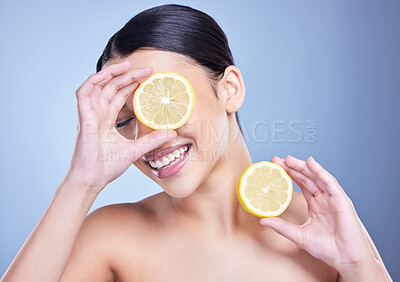 Buy stock photo Happy, lemon and woman laughing with smile for brightening face, beauty and wellness in studio. Blue background, healthy glow and female person with fruits for pores, vitamin c or diet for skincare