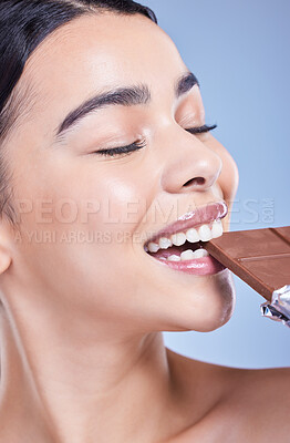 Buy stock photo Skincare, beauty and woman eating chocolate bar, sweets or treat in studio isolated on blue background. Makeup, nutrition and happy model with cocoa candy for diet, cosmetics and unhealthy sugar food