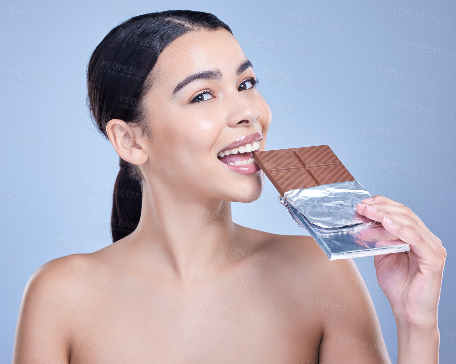 Buy stock photo Skincare, portrait and woman eating with chocolate bar and sweets in studio isolated on blue background. Makeup, face or happy model with cocoa candy for beauty diet, calories or unhealthy sugar food