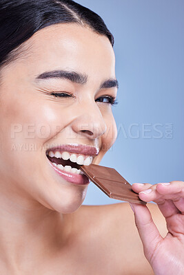 Buy stock photo Skincare, portrait and woman eating chocolate bar or wink in studio isolated on blue background. Face, beauty or happy model with cocoa candy for diet, cosmetic or healthy sugar food with antioxidant