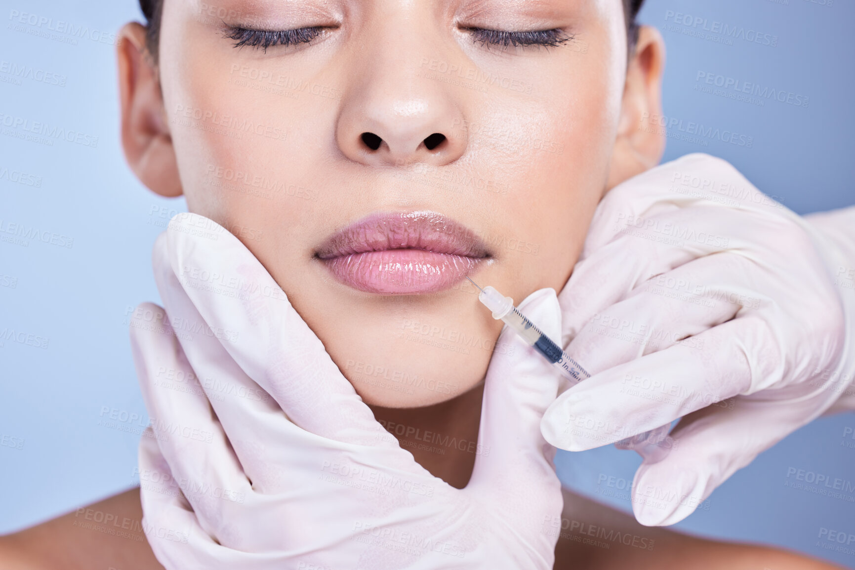 Buy stock photo Cosmetic surgery, woman and hands with filler in lips for facial transformation, beauty and change in studio. Syringe, surgeon or girl patient with injection for makeover treatment on blue background