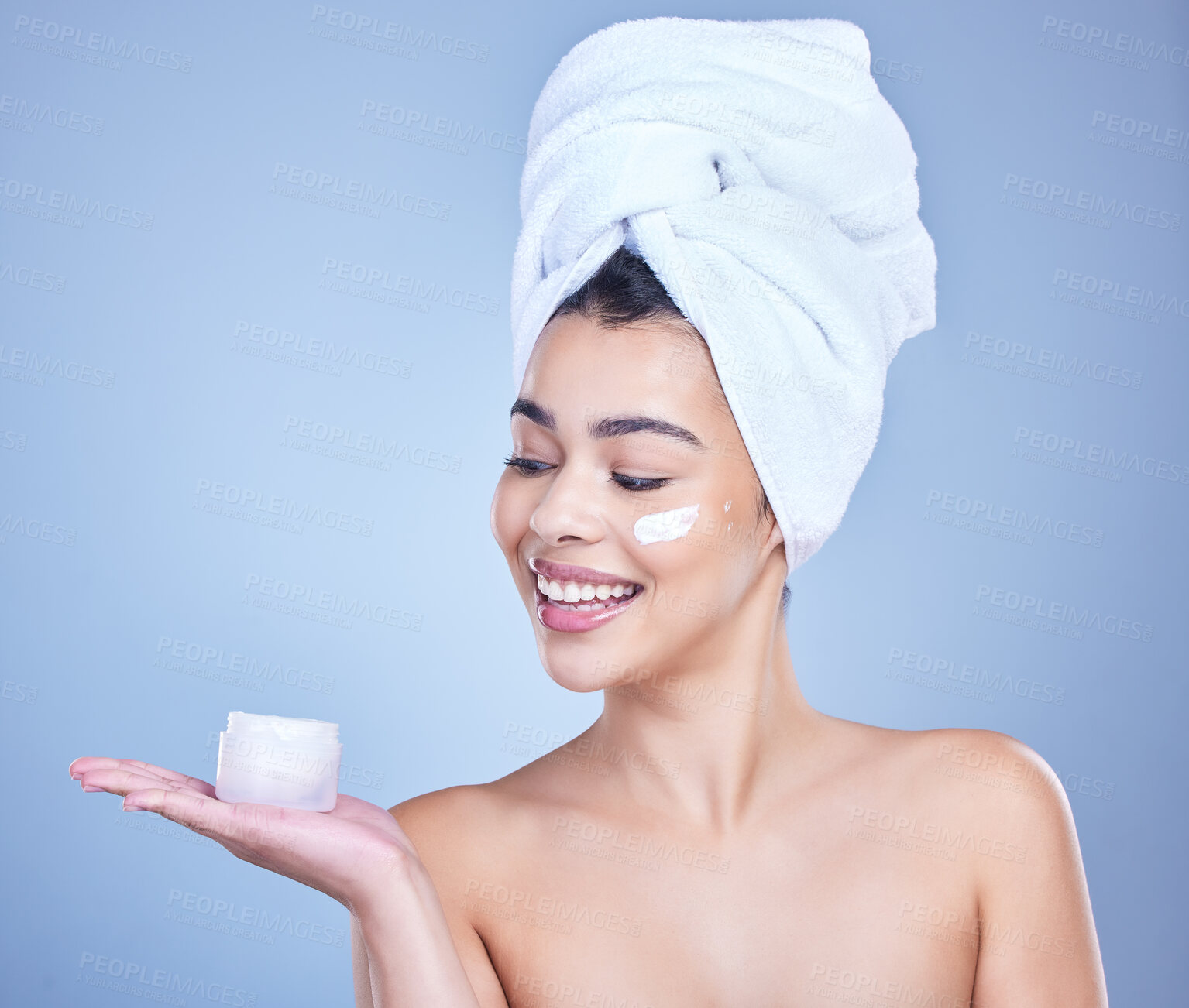 Buy stock photo Studio, woman face and cream with smile for skincare, application and tone wellness with cosmetics. Female model, beauty and treatment with lotion jar, moisturizer and results by blue background
