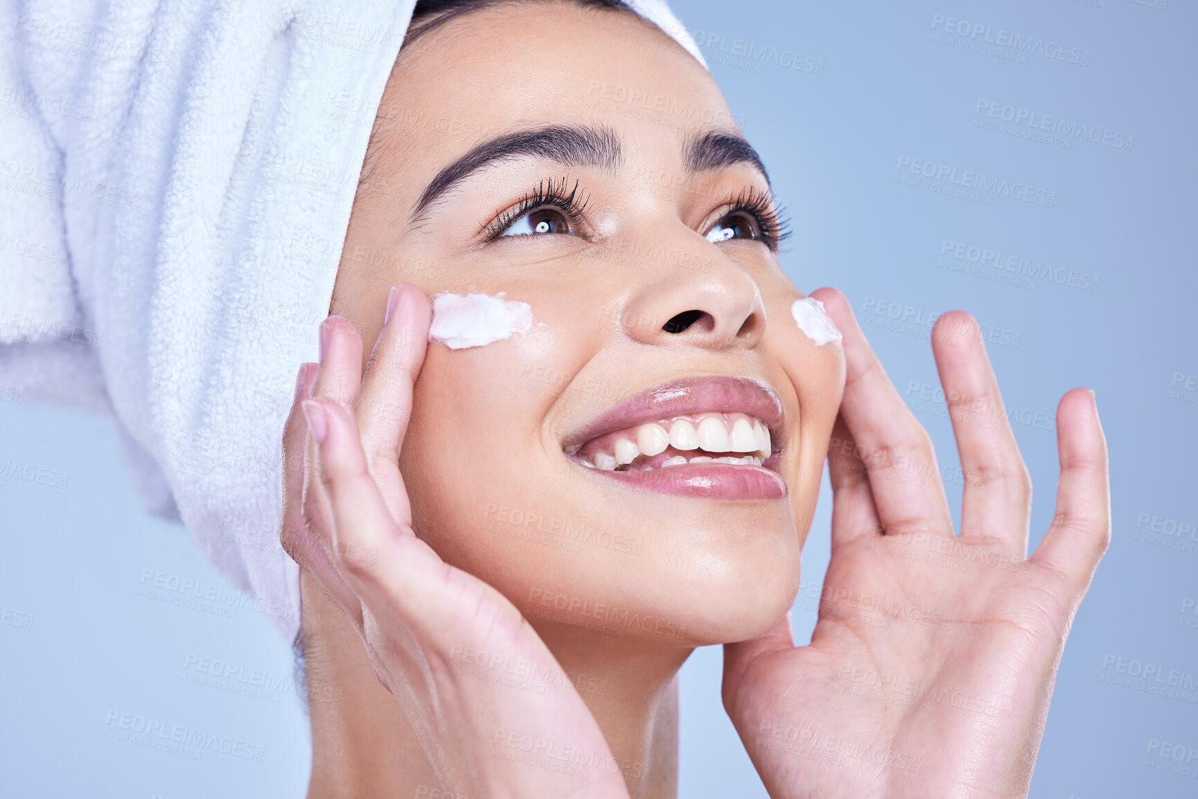 Buy stock photo Smile, woman and cosmetics with beauty, cream and dermatology on blue studio background. Happy person, smooth and model with towel, grooming routine and creme with treatment, wellness and clear skin