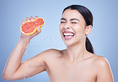 Buy stock photo Happy woman, grapefruit and skincare with vitamin C for natural nutrition on a blue studio background. Female person or model with smile, squeeze or fruit for juice, detox or antioxidant in wellness