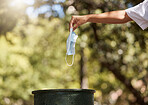 Closeup shot of a woman throwing her mask into a bin outside. The corona virus pandemic is ending. Saying goodbye to covid 19 restrictions and regulations. Your health is important. Protect yourself