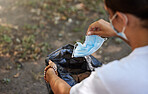 Closeup shot of a woman throwing her mask into a bin outside. The corona virus pandemic is ending. Saying goodbye to covid 19 restrictions and regulations. Your health is important. Protect yourself