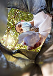 Portrait of a woman throwing trash into a bin outside while wearing a mask to protect herself from the corona virus pandemic. Unrecognizable female cleaning the environment. 