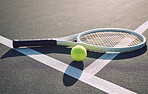 Above shot of a tennis racquet and tennis ball on a sports court. The only tools a professional tennis player needs to participate in their chosen sport. Six games per set to see who wins the match