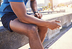 Closeup of unknown fit active mixed race man taking a break from his workout to breathe and relax. Unrecognizable man exhausted from his jog sitting before doing cardio and focus on his cardio