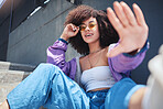 Portrait of young trendy beautiful mixed race woman with an afro smiling and posing alone outside. Hispanic woman wearing sunglasses and feeling happy. Fashionable African American woman in the city