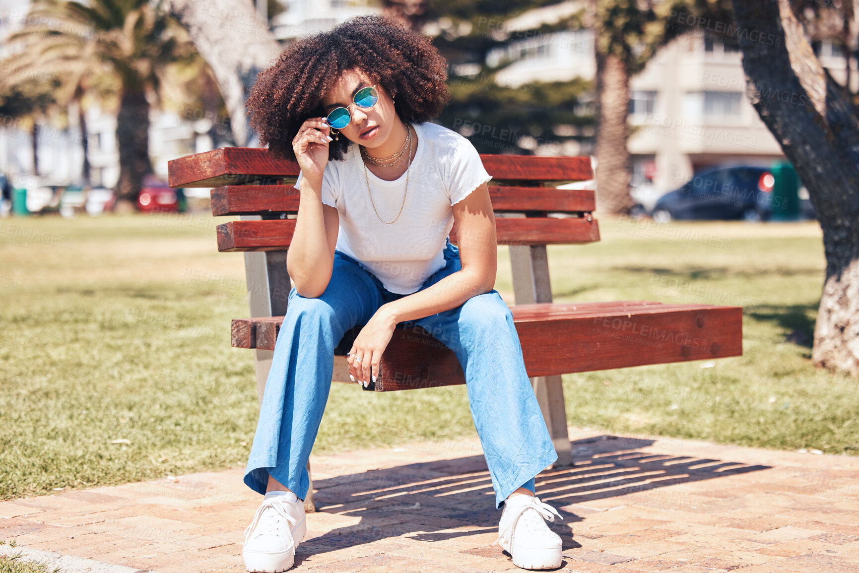 Buy stock photo Fashion, sunglasses and confident girl on park bench for trendy, style and vision in city. African woman, cool shades and outdoor to relax with streetwear, reflection and accessory in summer in USA