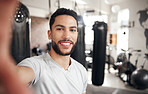 Portrait of one confident young hispanic man taking selfies while exercising in a gym. Happy mixed race guy smiling while working as a trainer and instructor in a fitness centre