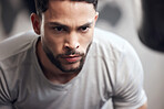 Closeup of one serious young hispanic man focused on his exercise session in a gym. Face of a determined mixed race guy getting mentally prepared to stay motivated and dedicated during a training workout in a fitness centre