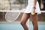 Closeup on the hands of a tennis player on the court. African american tennis player holding her ball and tennis racket on the court. Woman ready to compete in a tennis match at her club