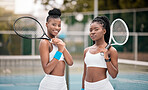 Two professional tennis players ready for a match. Young women holding their rackets on the tennis court. Two friends ready for tennis practice. Sporty, fit athletes ready for a game of tennis