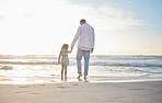 Rearview cute mixed race girl standing hand in hand with her father in the sea at the beach. A young man and his daughter holding hands while standing in the water and looking at the view at sunset