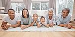 Happy and affectionate young mixed race family of six lying on the living room floor at home. Married couple with their mother, father and two cute daughters in the lounge. Granny and grandpa visit