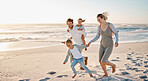 Carefree family playing on the beach together. Happy family on vacation by the ocean together. Little girls playing with their parents on holiday. Caucasian family bonding on the beach