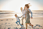 Carefree family having fun on the beach. Happy family playing on the beach on holiday. Caucasian family enjoying a beach vacation. Parents bonding with their children on the beach