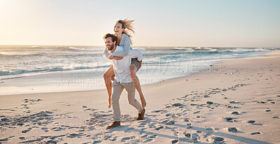 Buy stock photo Couple, walking and piggyback at beach for travel, bonding and sunset while on vacation together with smile. Man, woman and carrying outdoor by sea for love, relationship and adventure on holiday