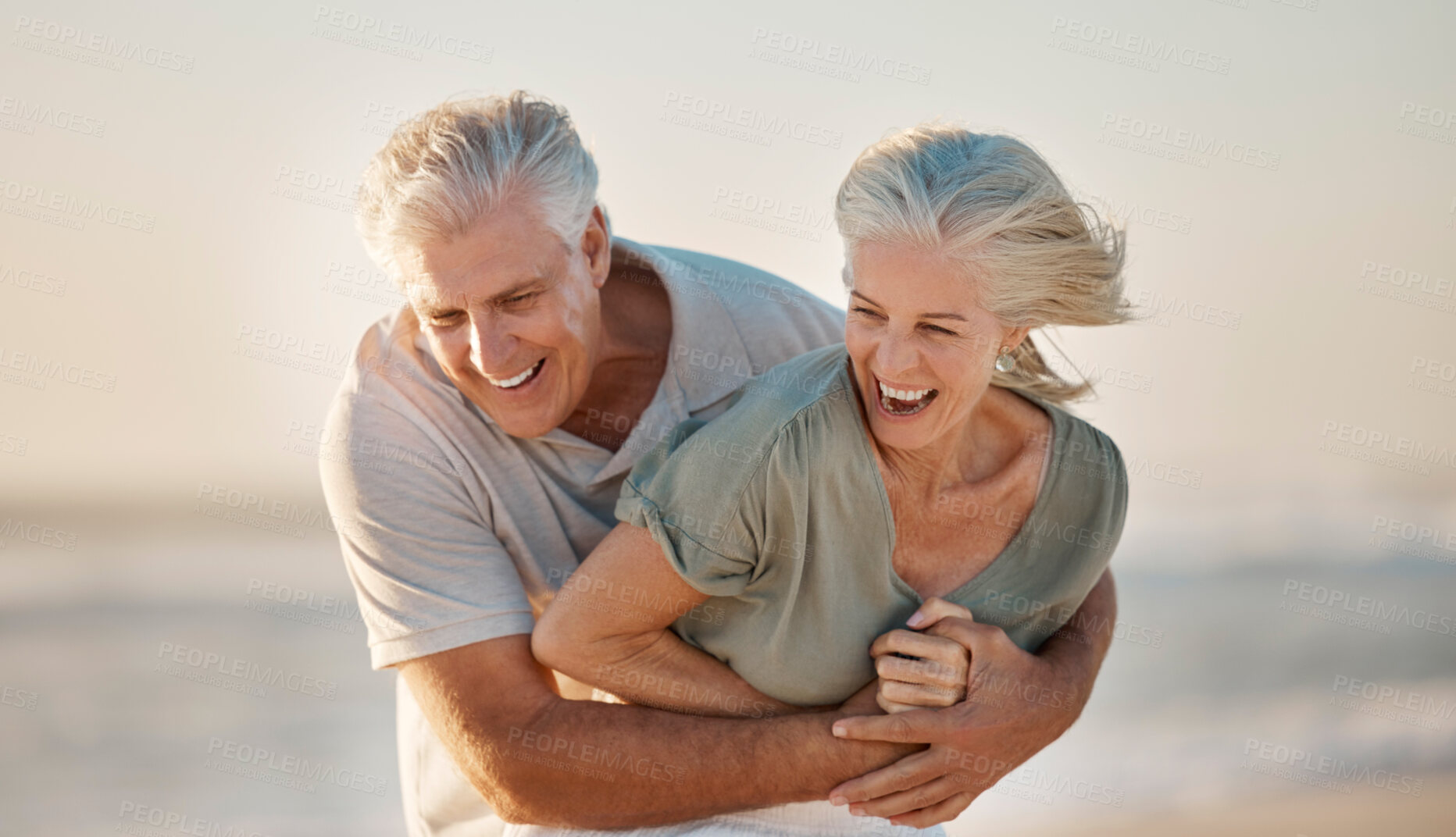 Buy stock photo Hug, laughing and love with old couple on beach together for holiday, travel or vacation in summer. Funny, romance or smile with elderly man and woman embracing on coast for bonding or having fun