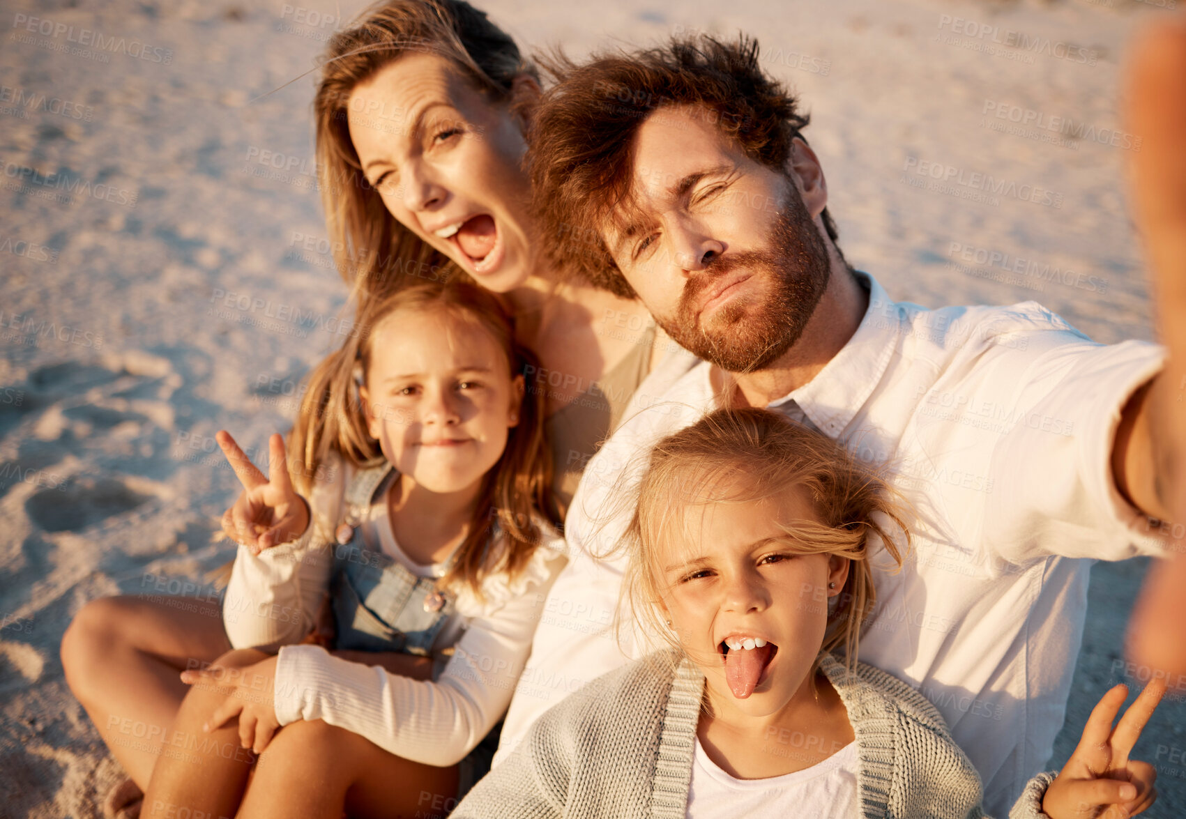 Buy stock photo Mom, dad and children in selfie at beach, funny face or smile with care, love or tongue out for summer memory. Father, mother and daughter kids with peace sign, family or portrait on holiday in Spain