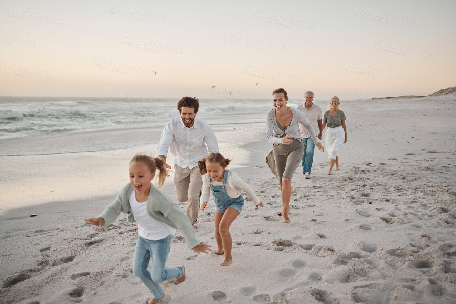 Buy stock photo Parents, children and playful with running, beach and excited with grandparents on vacation in summer. Big family, kids and generations at sunset, care and bonding with games by ocean in Spain