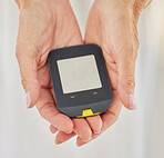 Closeup of a senior diabetic woman checking her blood sugar glucose levels with a diabetes reading strips machine. One unknown elderly woman doing a blood sugar reading at home