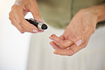 Closeup of a senior diabetic woman checking her blood sugar glucose levels with a prick to the finger. One unknown elderly woman getting a blood sugar reading at home