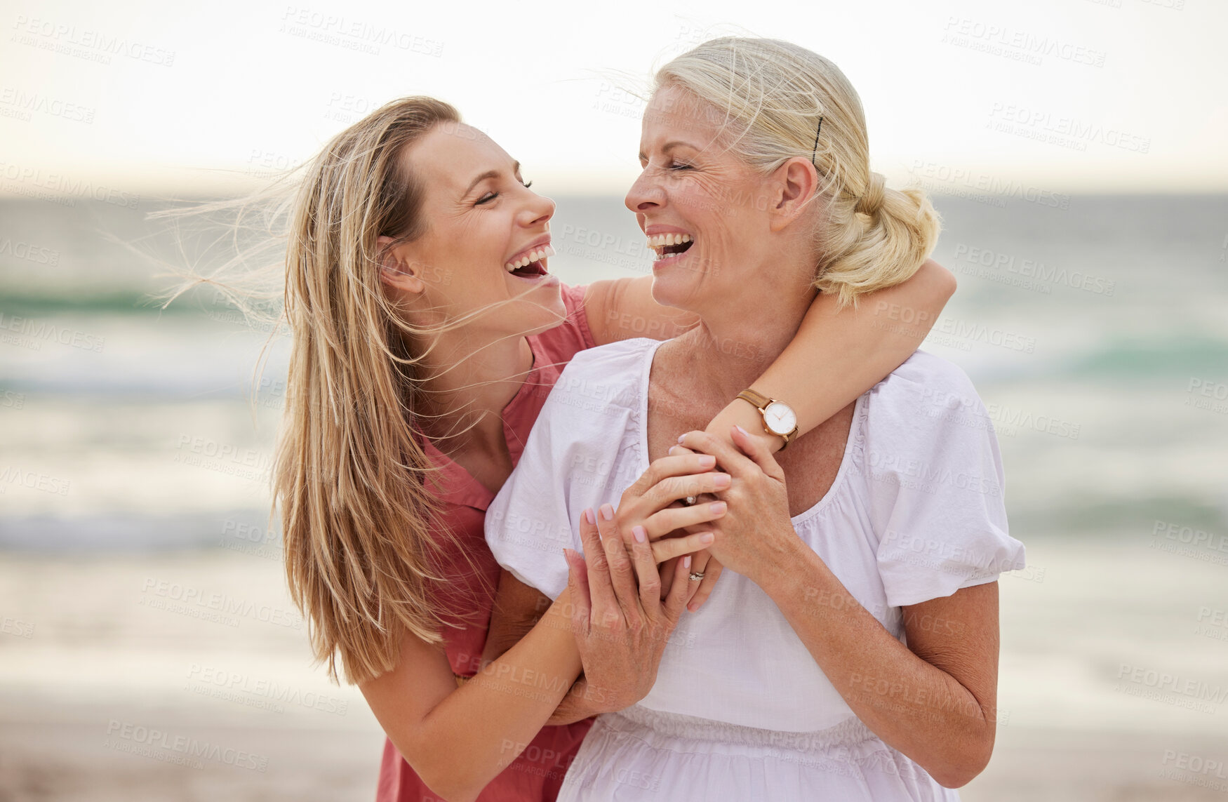 Buy stock photo Smile, beach and senior mom with daughter for bonding holiday, love and embrace on weekend travel. Nature, mother and woman laughing on ocean adventure together with hug, fun and island vacation.