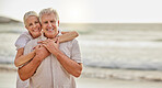 Portrait of a happy senior caucasian couple standing and embracing each other on a day out at the beach. Mature husband and wife smiling and showing affection in nature