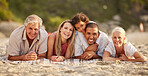 Portrait of a senior caucasian couple at the beach with their children and grandchild. Mixed race family relaxing on the beach having fun and bonding